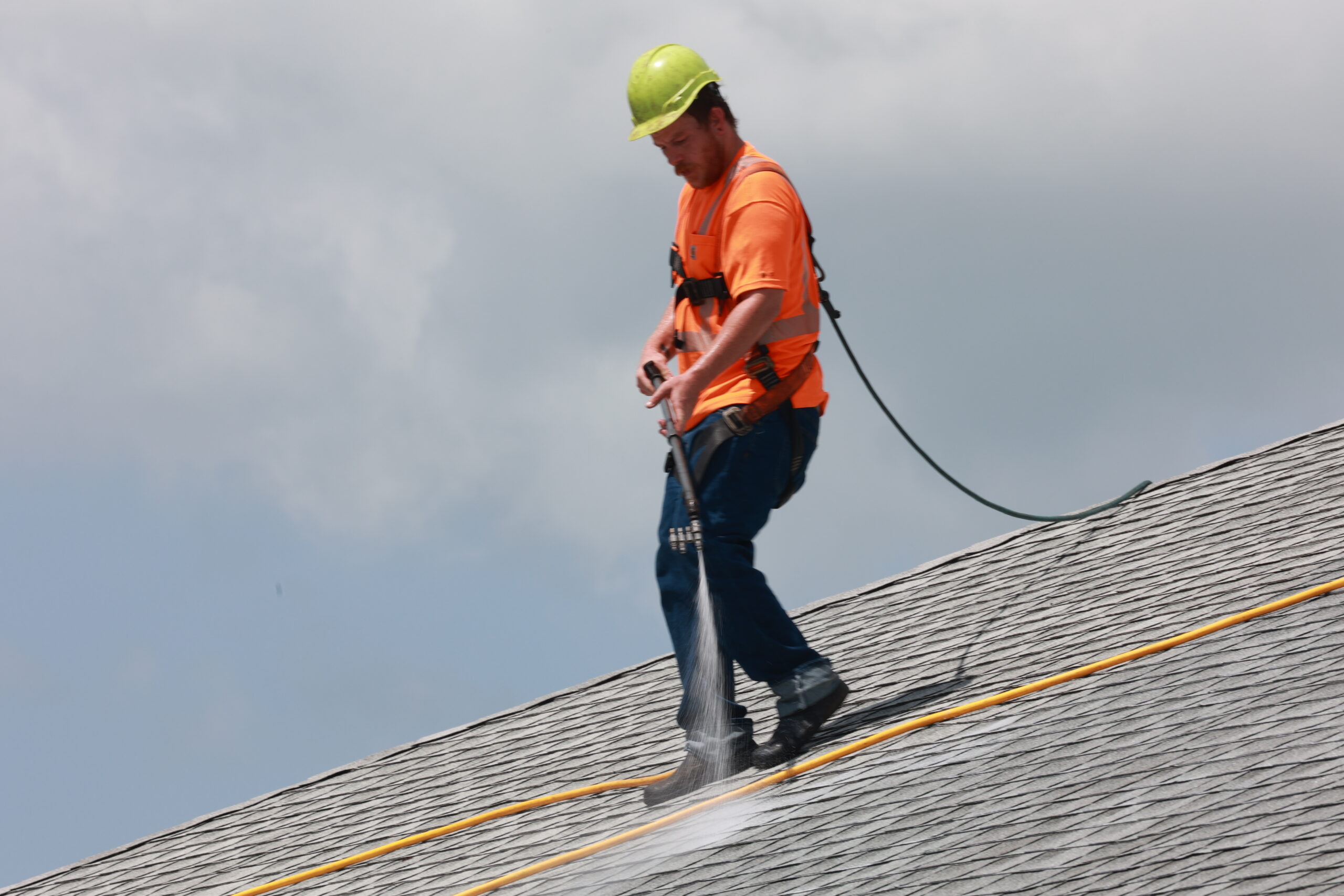Worker pressure washing roof shingles-Roof Rejuvenate pros