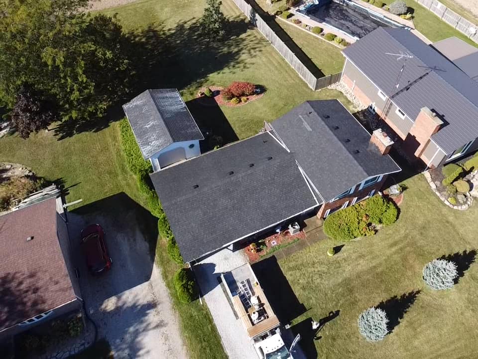 Aerial view of house with new dark roof- Roof Rejuvenate pros